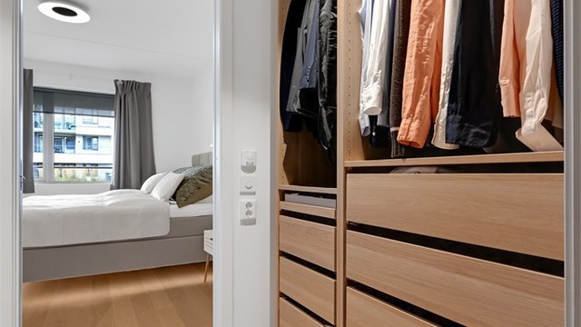 Innholdsrikt walk-in closet innredet med skuffer og oppheng, utstyrt med vannbåren gulvvarme.
