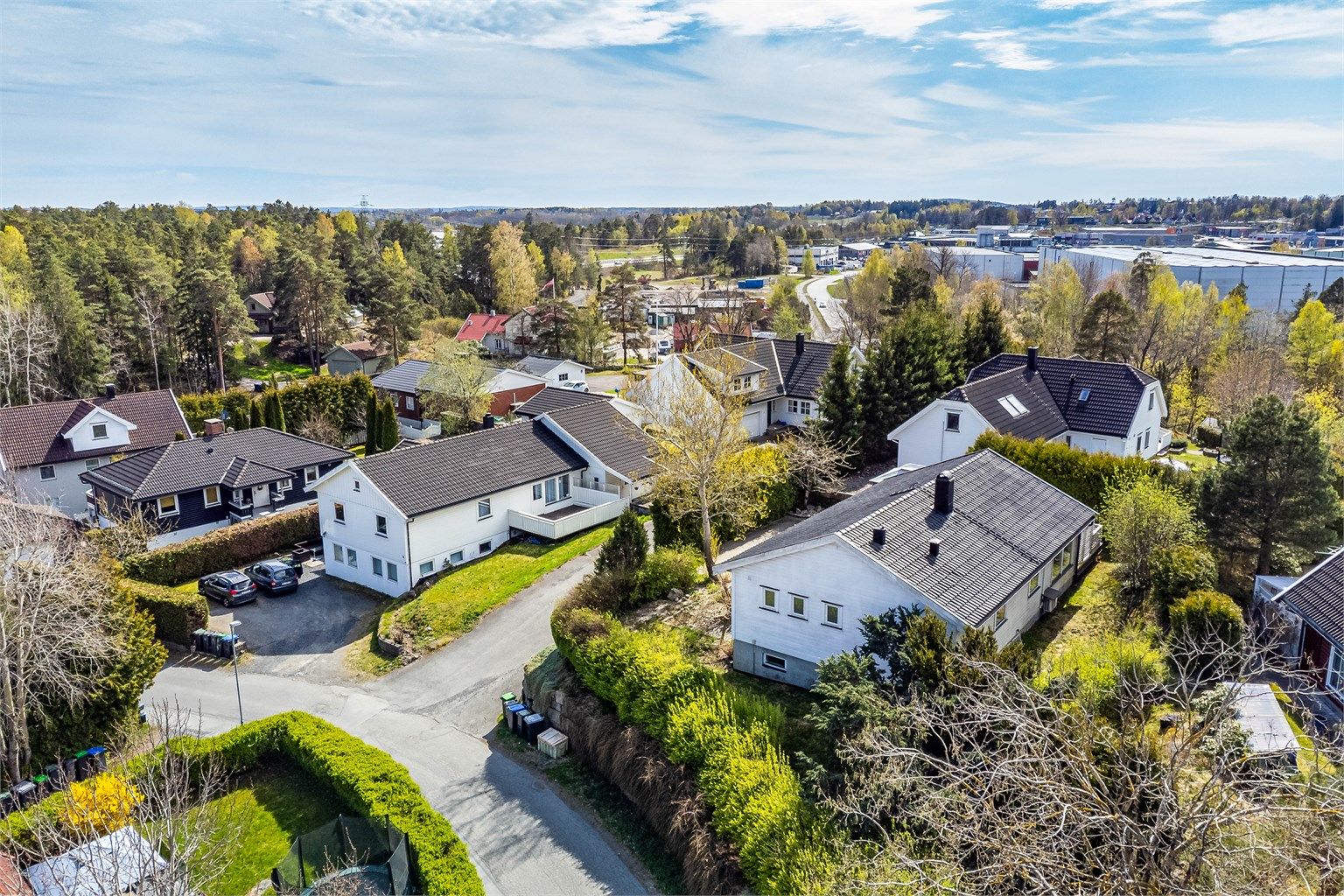 En lettstelt hage med gressplen er anlagt rundt boligens østre, nordre og vestre side - innrammet av tettvoksende hekker.