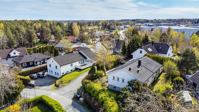 En lettstelt hage med gressplen er anlagt rundt boligens østre, nordre og vestre side - innrammet av tettvoksende hekker.