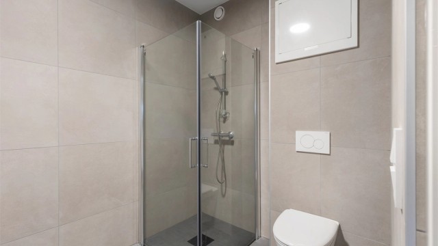 Videre er badet utstyrt med servantskap med speil og lys, vegghengt toalett og dusjhjørne.
