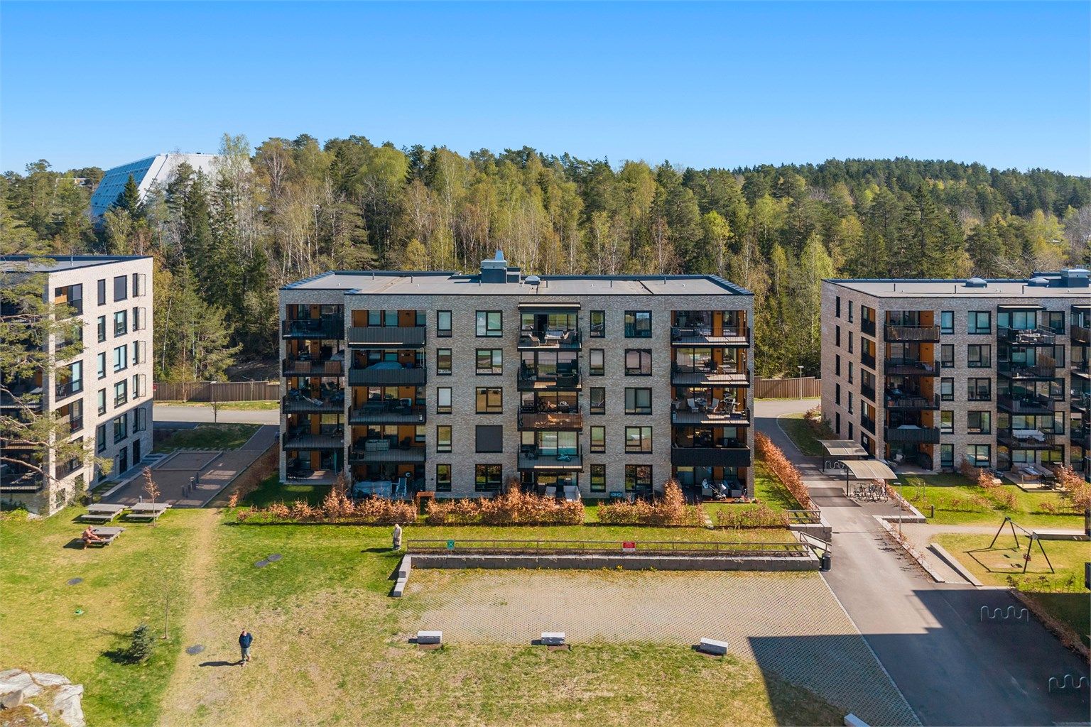 Området består av moderne leilighetsbygg med store, grønne fellesarealer mellom bygningene.