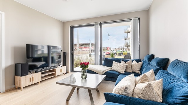 Store vinduer gir gode lysforhold og setter et luftig preg på stuen. Skyve-/hevedøren sikrer enkel tilgang til utearealet.