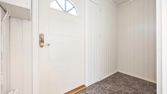 Entré med gulvbelegg og malt panel på veggene.