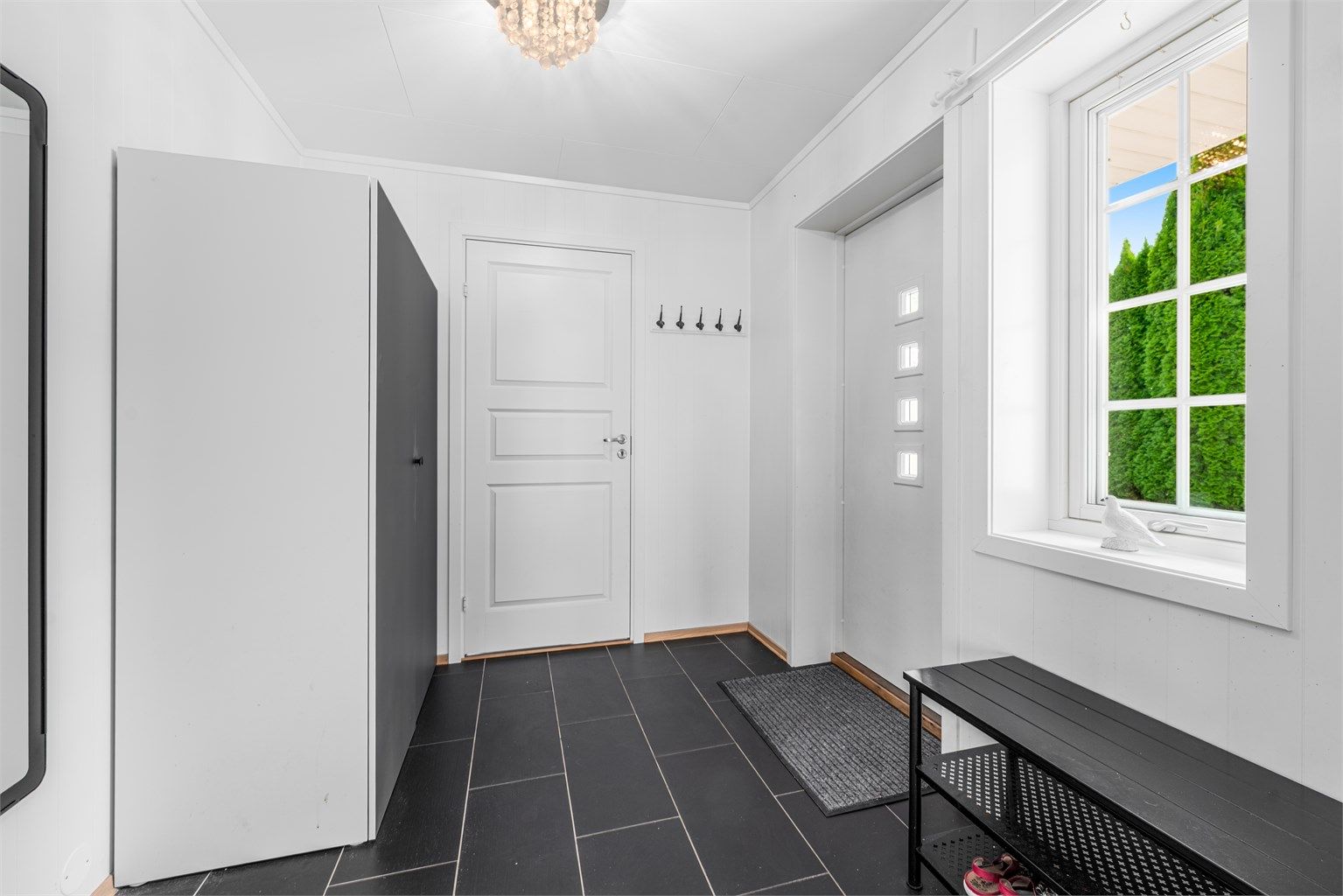 En romslig entré ønsker deg velkommen. Her kan du henge av deg jakken og ta av deg skoene før du tar turen videre i ditt nye hjem. Varmekabler i gulv. Inngang til praktisk innebod. 