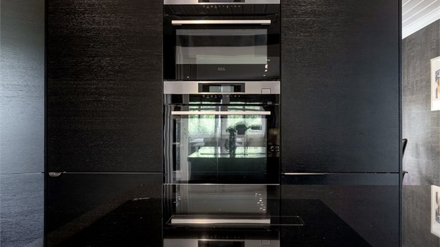 Høyskap med integrerte hvitevarer for et rent og helhetlig design.