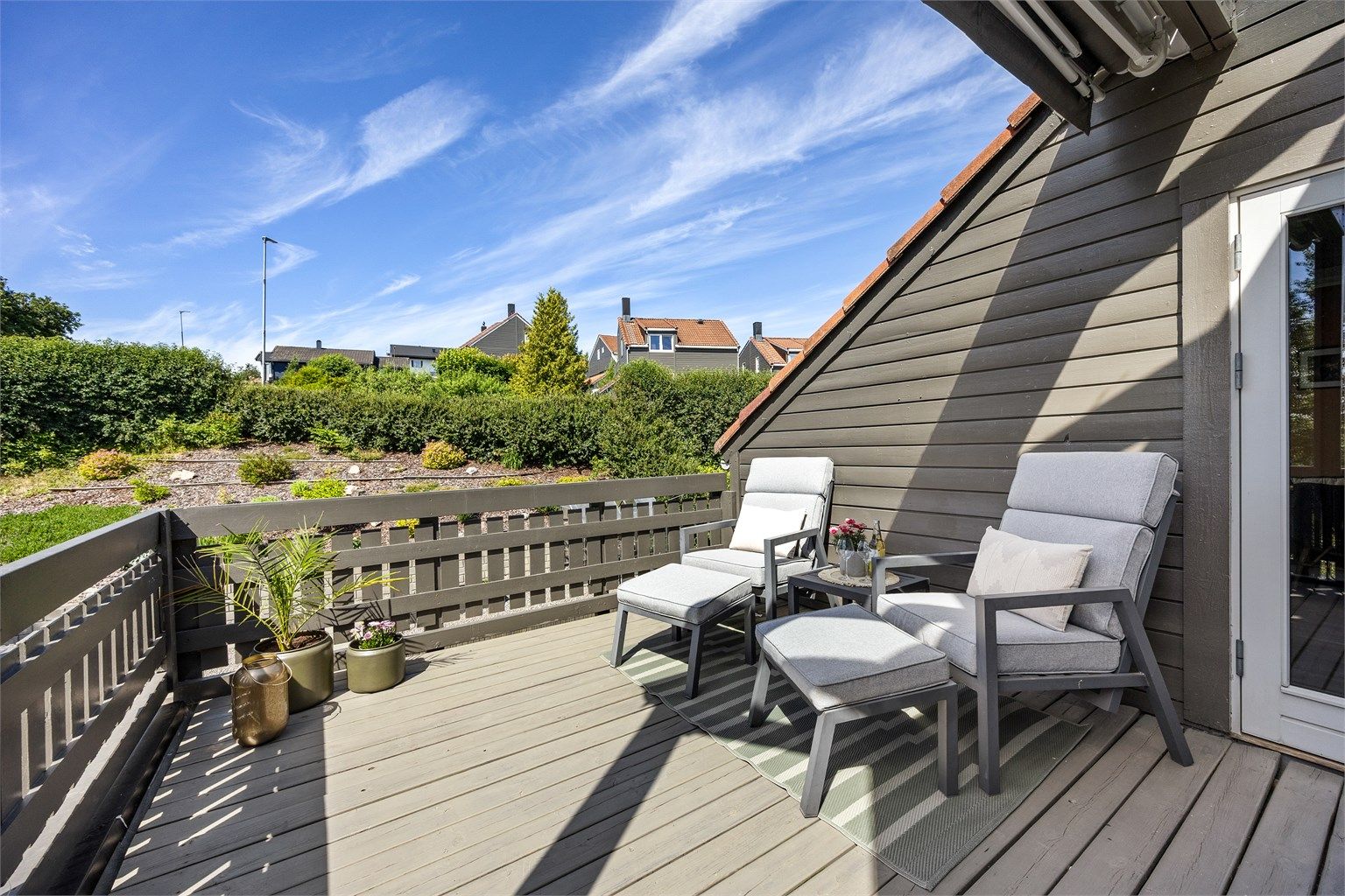 Terrassen har rekkverk i trekonstruksjon og terrassebord på bjelkelag.