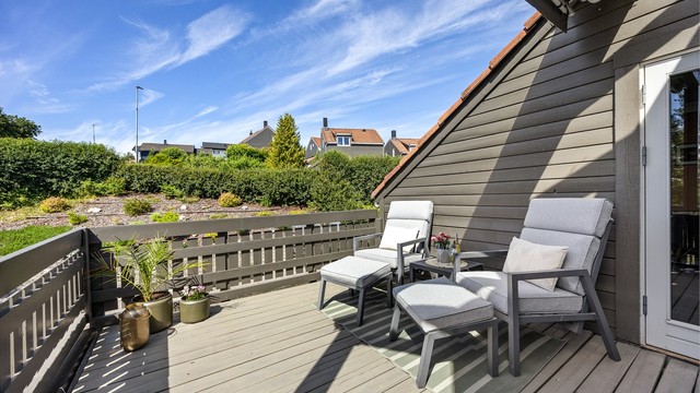 Terrassen har rekkverk i trekonstruksjon og terrassebord på bjelkelag.