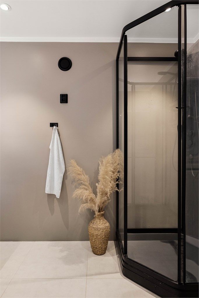 Badet har flislagt gulv med varme og vegger i malte flater, nedsenket himling med downlights.