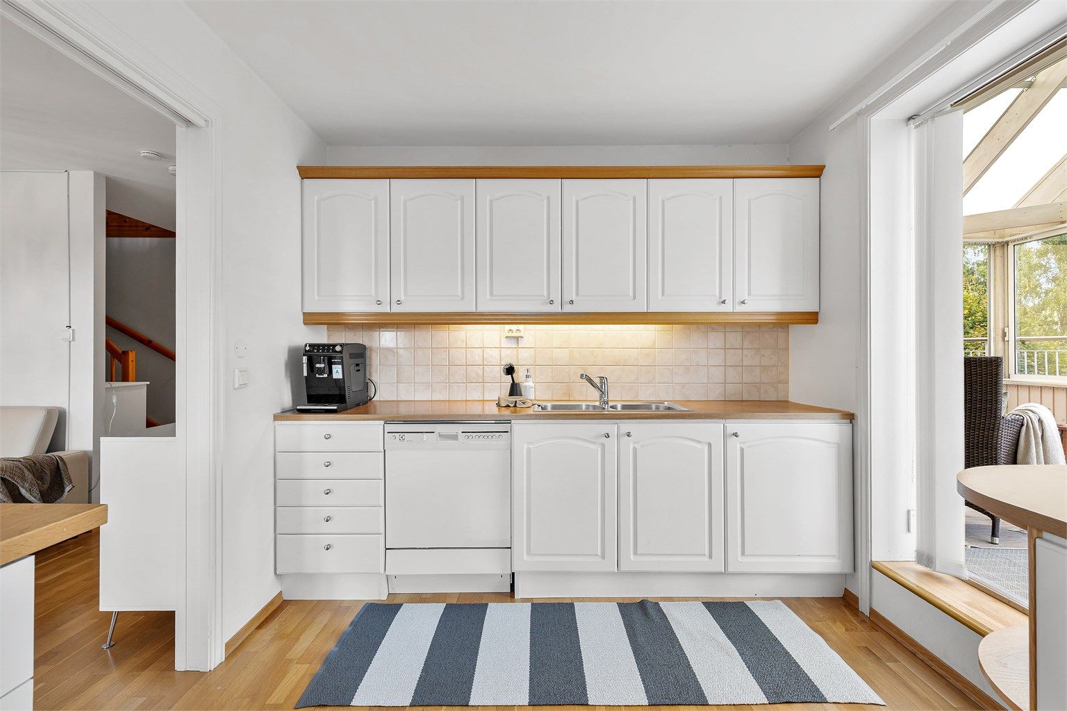 Kjøkkeninnredning fra byggeår med profilerte fronter og benkeplate med laminert overflate. Kjøkkenvask med armatur.