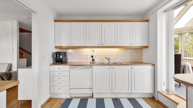 Kjøkkeninnredning fra byggeår med profilerte fronter og benkeplate med laminert overflate. Kjøkkenvask med armatur.