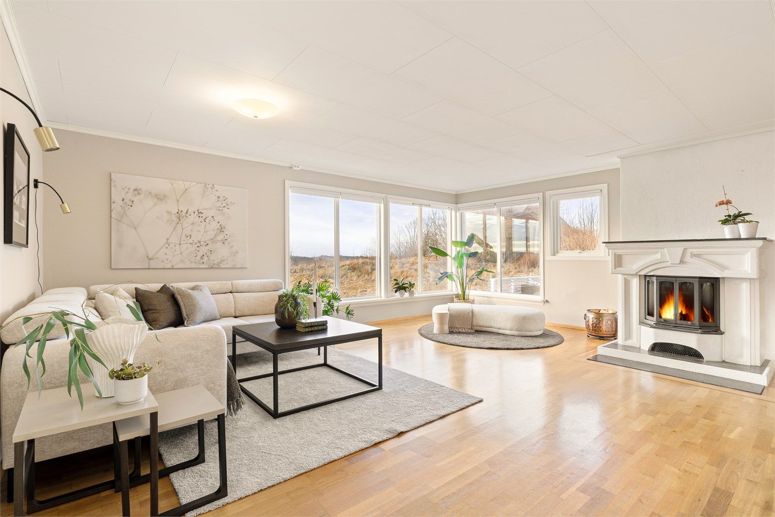 Lys og romslig stue med store vindusflater.