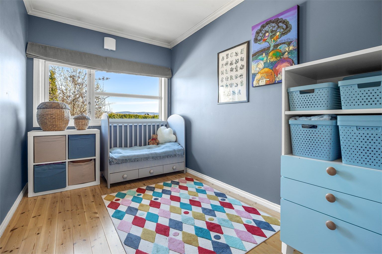 Et av de tre soverommene i underetasjen, med gulvbord av tre og plass til seng og oppbevaring.