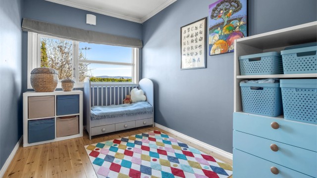 Et av de tre soverommene i underetasjen, med gulvbord av tre og plass til seng og oppbevaring.