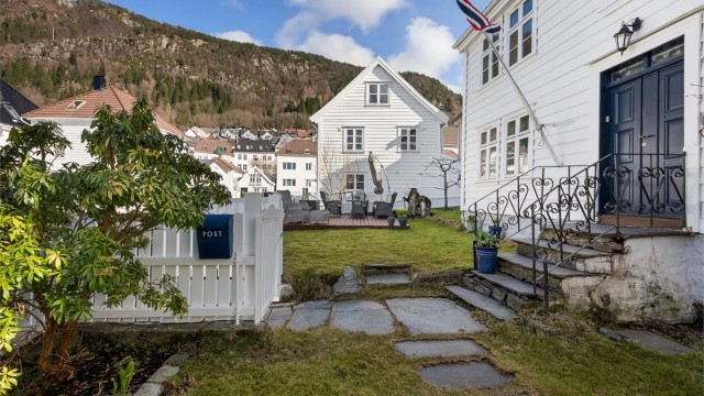Eiendommen er fint rammet inn av hvitmalt stakittgjerde og med skiferheller frem til inngangen.
Foto: Her Fotograf