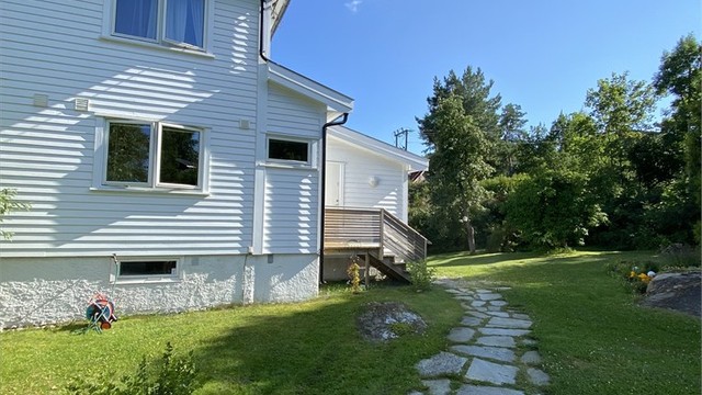 Eiendommen er et hageparadis på sommeren som både er praktisk og idyllisk, og du finner en skiferbelagt adkomst til huset. (privat foto)