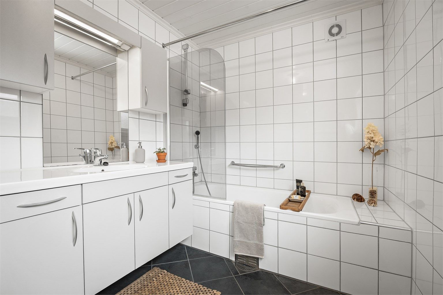 Lyst og pent bad fra 2009 med gulvvarme. Heldekkende servant over servantskap i hvit og glatt utførelse.