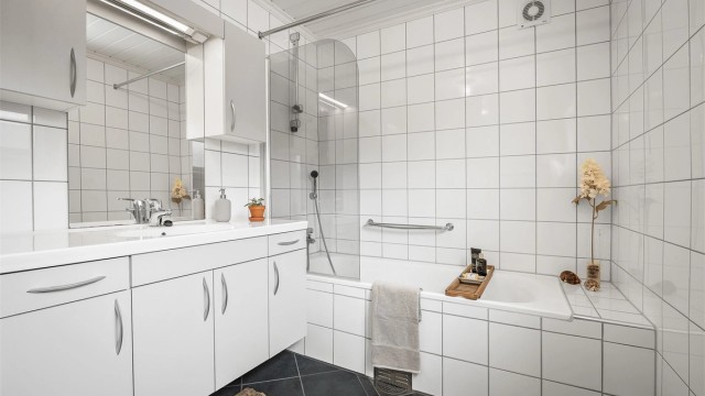 Lyst og pent bad fra 2009 med gulvvarme. Heldekkende servant over servantskap i hvit og glatt utførelse.