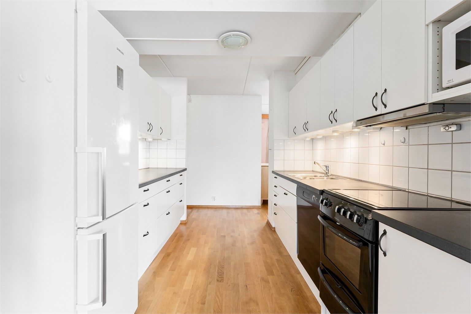 Kjøkkenet har slette fronter, laminat benkeplate og nedfelt oppvaskkum i rustfritt stål med ettgreps armatur. Fliser på vegg, benkebelysning og stikkontakter over benk