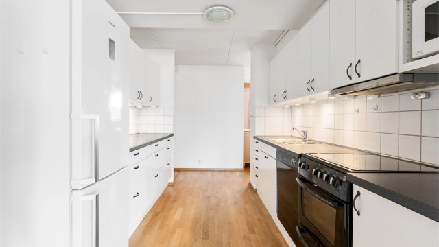 Kjøkkenet har slette fronter, laminat benkeplate og nedfelt oppvaskkum i rustfritt stål med ettgreps armatur. Fliser på vegg, benkebelysning og stikkontakter over benk