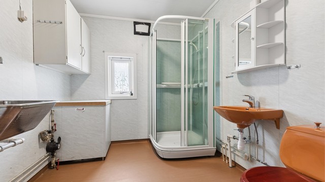 Badet har en praktisk utforming med dusjkabinett, servant, toalett og opplegg for vaskemaskin, samt utslagsvask.