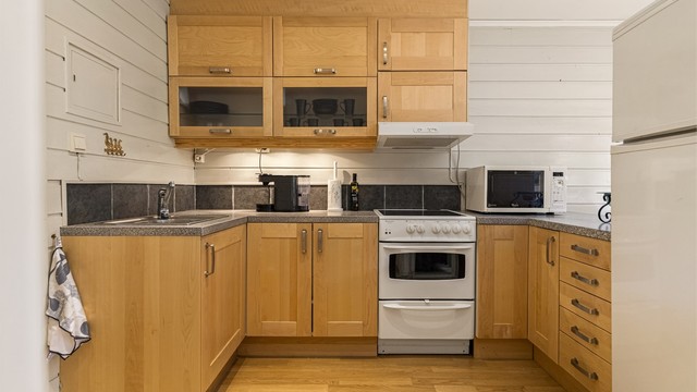 Kjøkkeninnredning fra Ikea med laminert benkeplate og fliser over benken. Det er laminatgulv med gulvvarme.