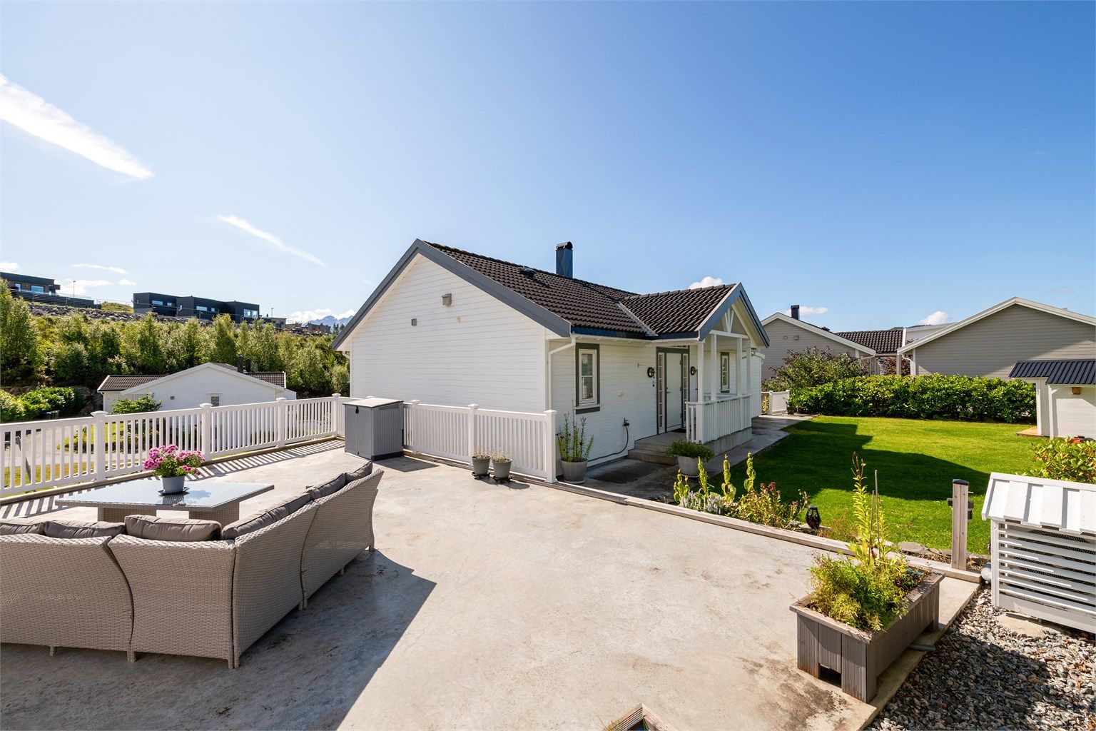 Stor takterrasse over garasjen i betongkonstruksjon med hvitt rekkverk.