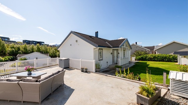 Stor takterrasse over garasjen i betongkonstruksjon med hvitt rekkverk.