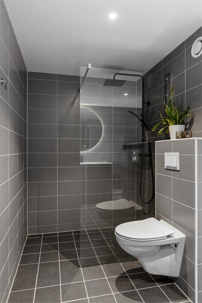 Romslig dusjnisje med glassvegg og regnfallsdusj.