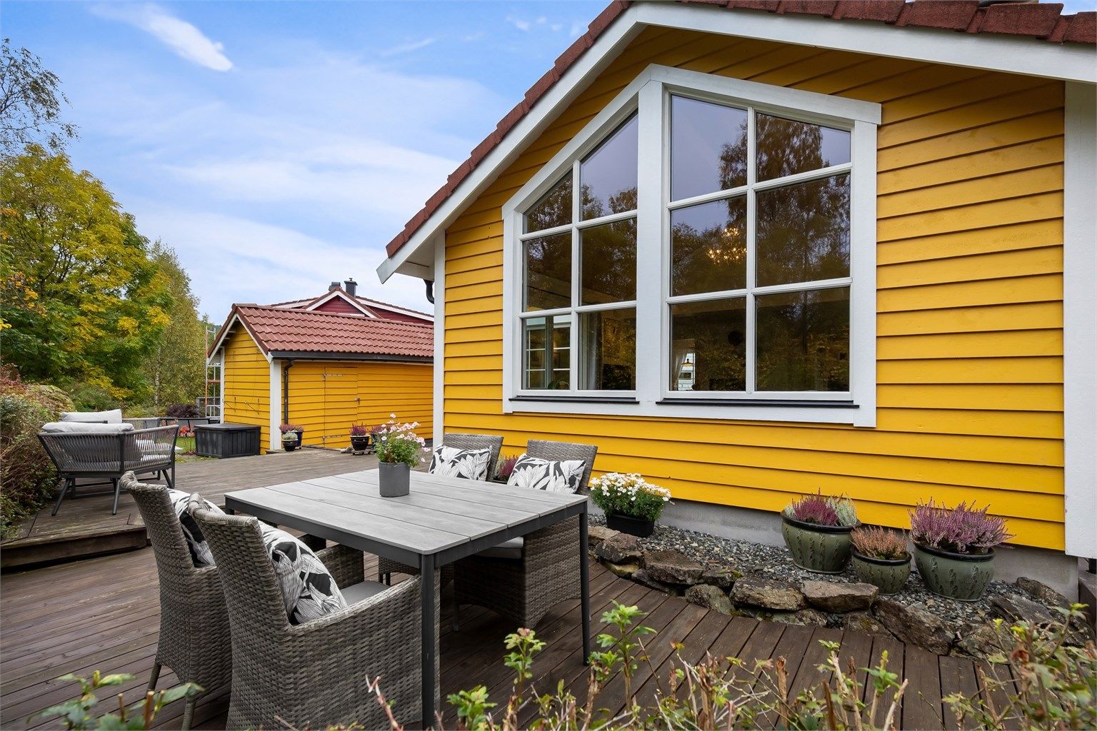 Skjermet uteplass med integrert blomsterbed og god kontakt med den omkringliggende hagen.