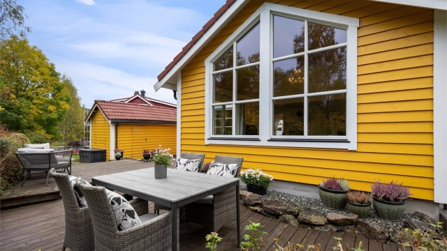 Skjermet uteplass med integrert blomsterbed og god kontakt med den omkringliggende hagen.
