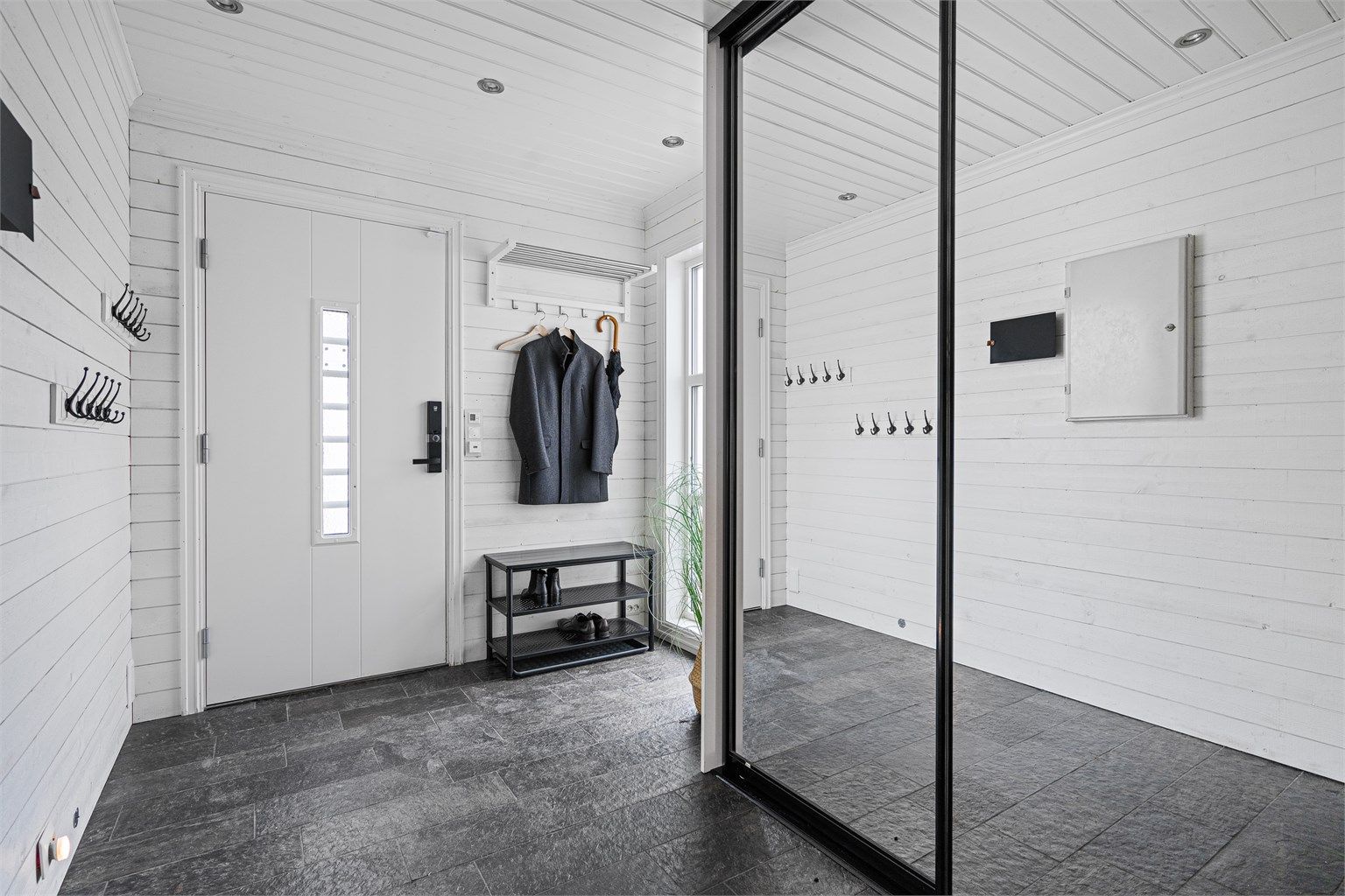 Entré med skiferfliser på gulv, vegger med lyst panel og spotter i tak. Entré er romslig og har plass til f.eks en barnevogn inne, dersom man skulle trenge det.