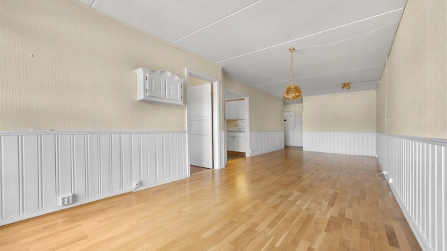 Stuen har parkett på gulvet og vegger med malt brystningspanel.