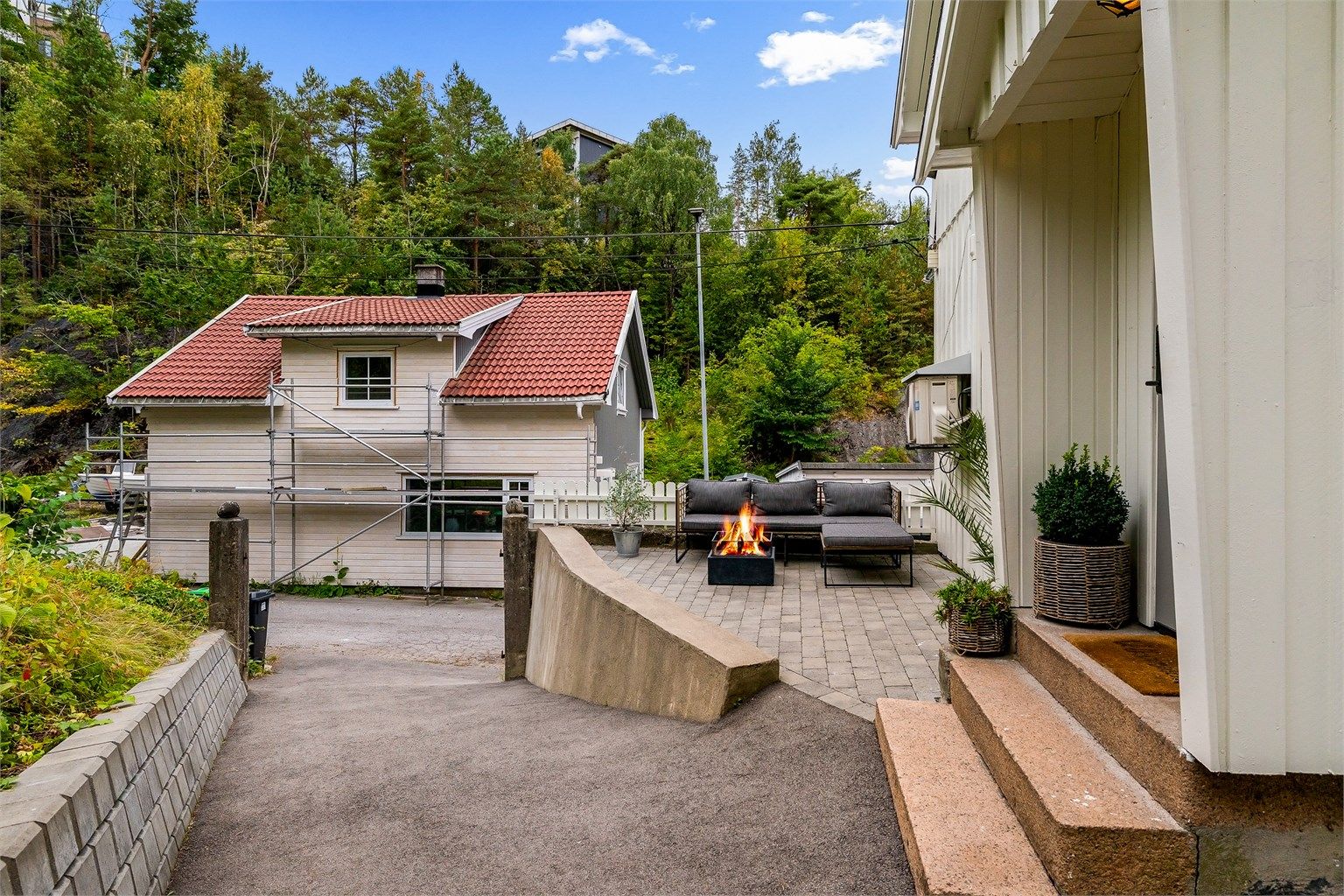 På begges sider av huset er det fine uteplasser, her ved inngangspartiet. Adkomst til boligen er asfaltert og forstøttningsmurer er nylig satt opp.
