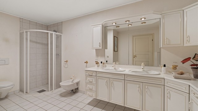Hovedbadet er innredet med dobbel servant i underskap, vegghengt toalett, bidet og dusjhjørne.