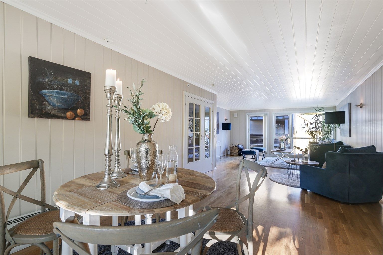 Åpen stue/kjøkkenløsning innredet med spisemøblement.