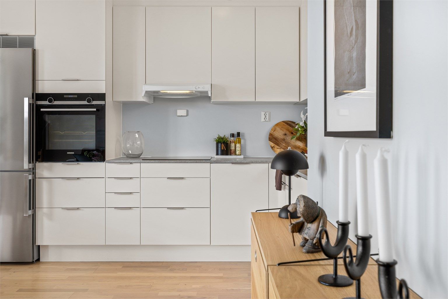 Kjøkkenet har et moderne uttrykk med lyse fronter og en gjennomført materialpalett.