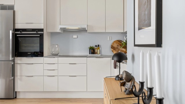 Kjøkkenet har et moderne uttrykk med lyse fronter og en gjennomført materialpalett.