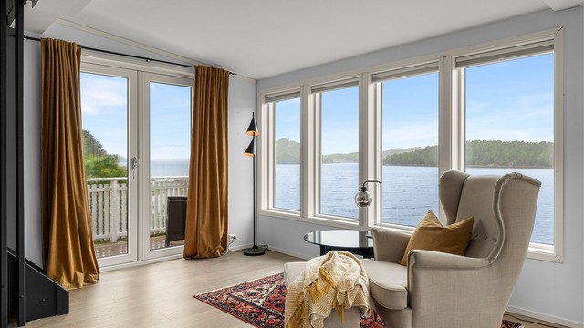 Her kan du nyte sjøutsikten fra godstolen – en rolig og stemningsfull sone med utgang til veranda.