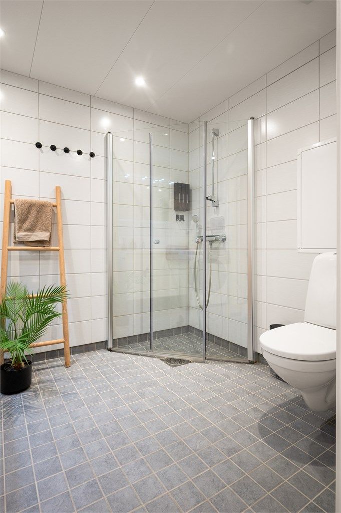 Badet er utstyrt med vegghengt toalett og dusjhjørne med innfellbare glassdører i herdet glass