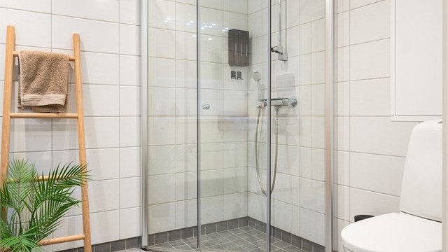 Badet er utstyrt med vegghengt toalett og dusjhjørne med innfellbare glassdører i herdet glass