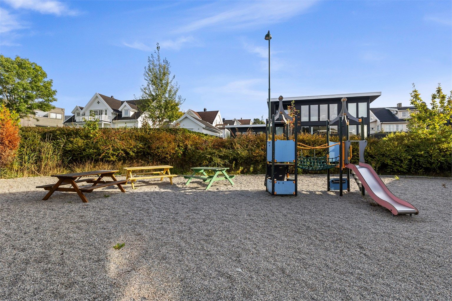 Borettslagets felles lekeplass med klatrestativ, rutsjebane og benker.