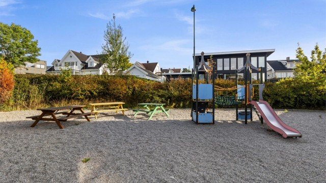 Borettslagets felles lekeplass med klatrestativ, rutsjebane og benker.