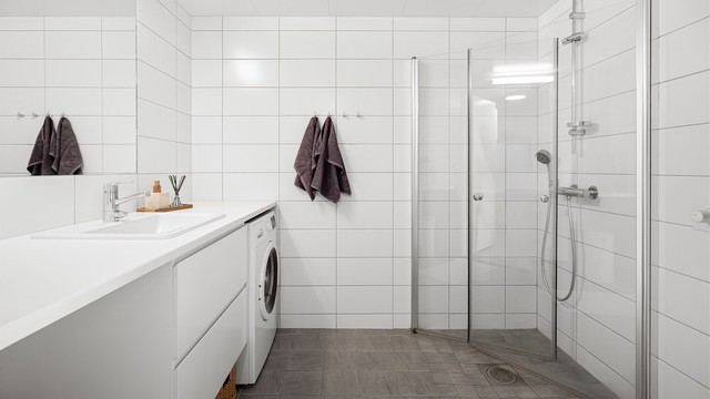 Videre er det dusjhjørne med glassdører og vegghengt dusjarmatur.