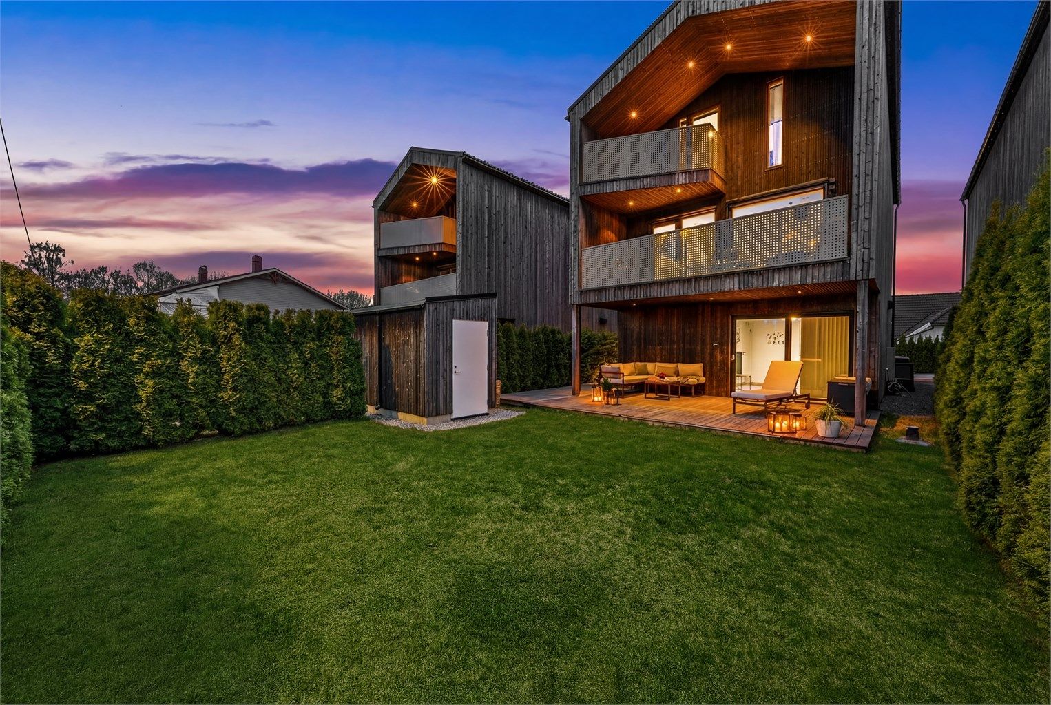 Boligens tre plan sett fra hagen på kveldstid. Foto: Flyende Film AS (Øyvind Borgersen)