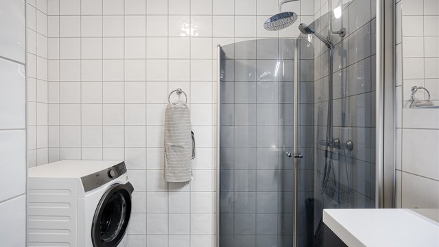 Badet er kombinert vaskerom med opplegg for vaskemaskin. Dusjhjørnet har svingdører og regnfallsdusj.