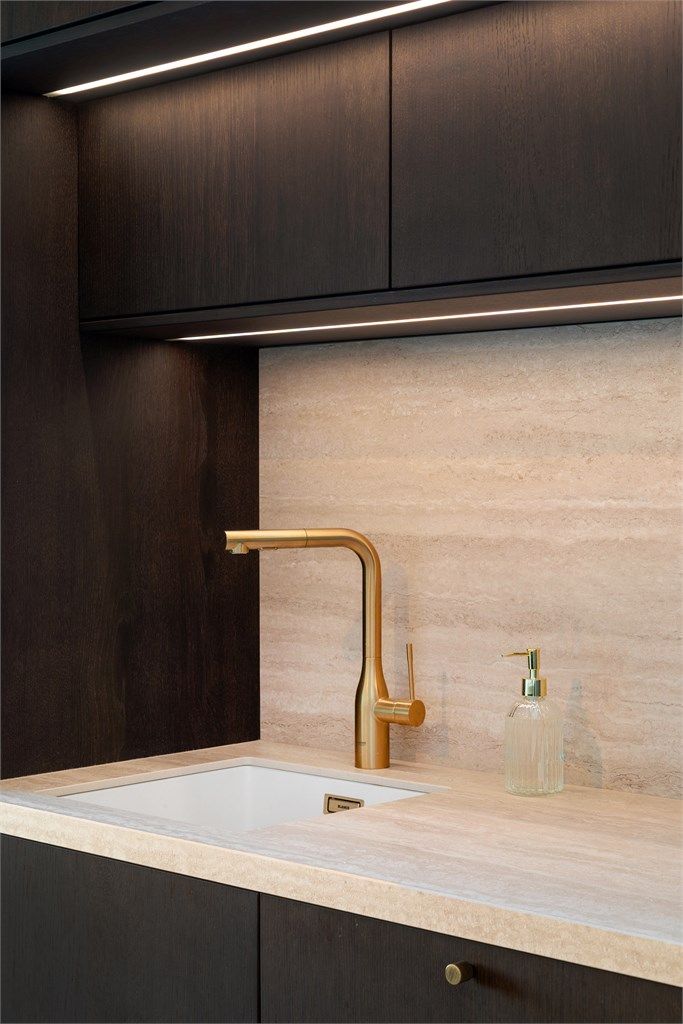 Eksklusiv benkeplate, Marazzi Travertino Classico Satin fra Nerostein, står godt til innredningen. Armatur fra Grohe med messingfinish og integrert belysning under overskapene