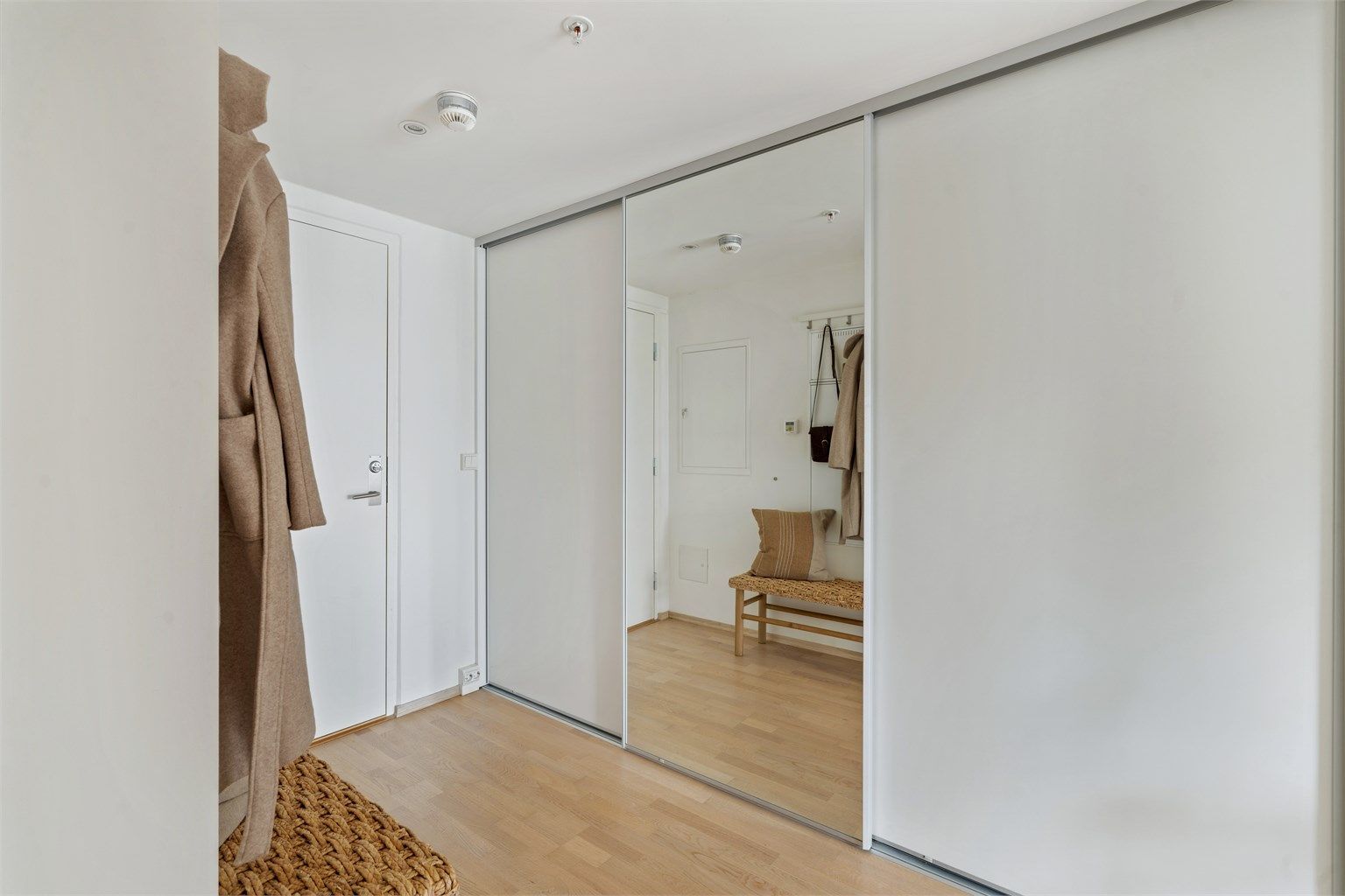Romslig gang med stor skyvedørsgarderobe for effektiv oppbevaring.