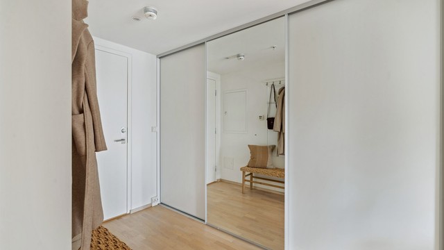 Romslig gang med stor skyvedørsgarderobe for effektiv oppbevaring.