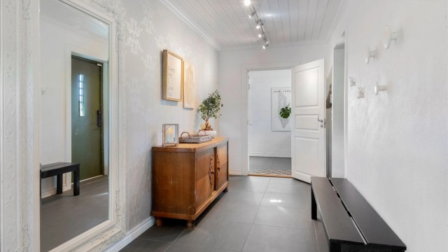 Gangen har en dekorativ fondvegg med tapet og det er plass til knagger, helspeil, samt oppbevaringsmøbel.