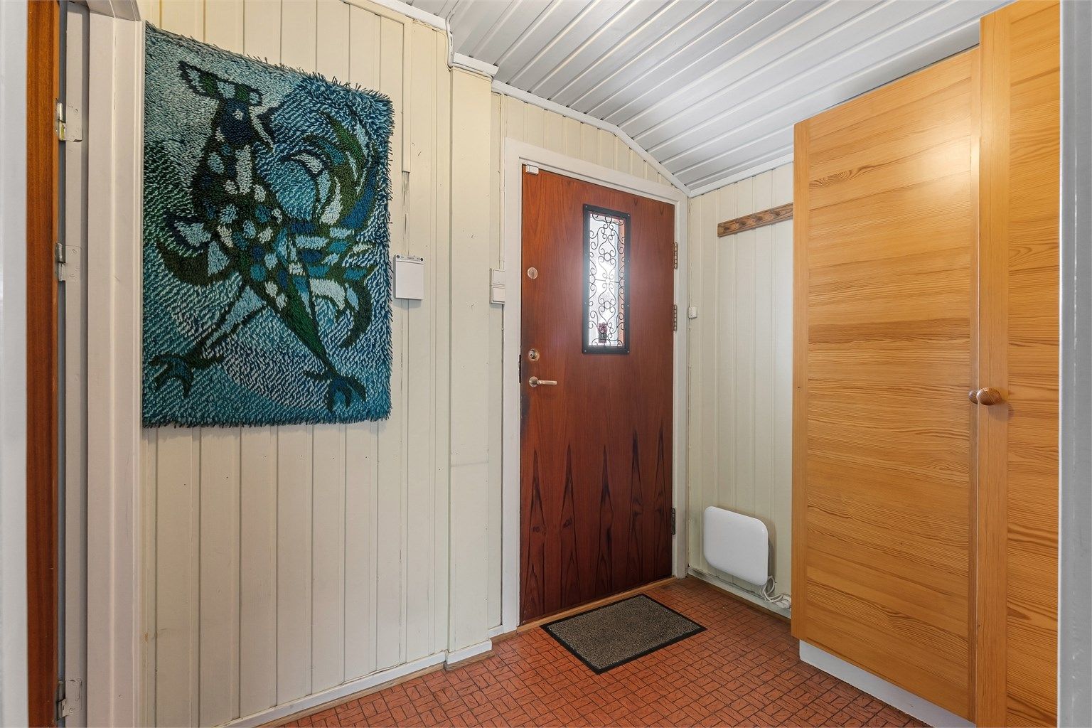 Overbygget inngangsparti med entrédør utstyrt med sikkerhetslås.
